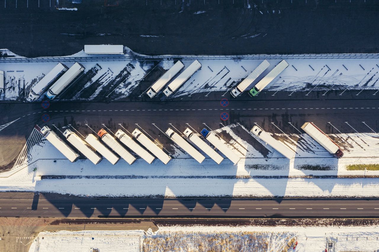 Vue aérienne d'une cour de remorques stationnées en rangées, neige et ombres longues